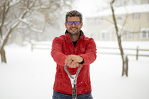 man with a shovel standing in snow 