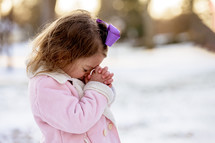 girl child praying outdoors in snow 