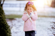 toddler girl standing outdoors praying in winter 