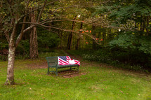 American flag and Bible on bench in park in evening