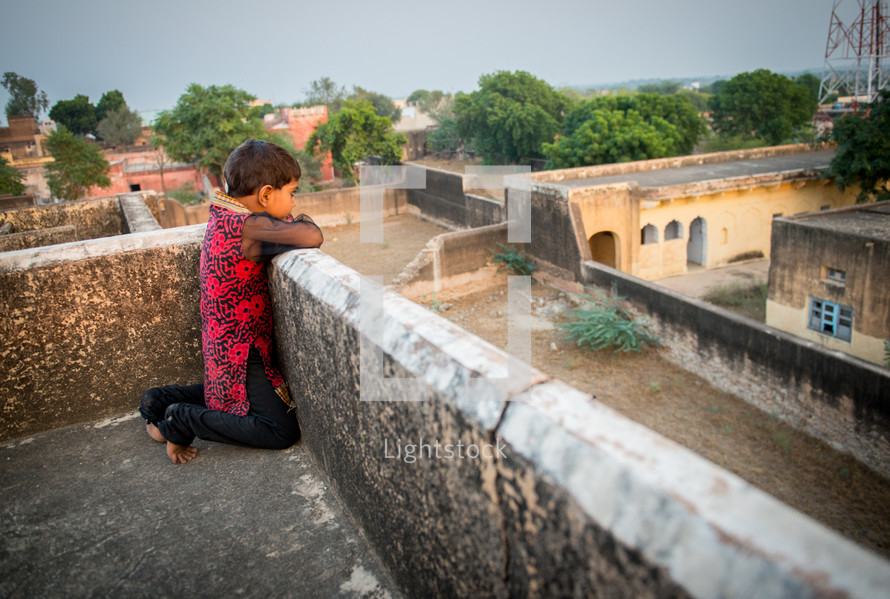 a child looking over a rooftop in India 