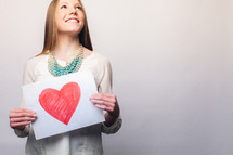 teen girl holding a drawing of a red heart 