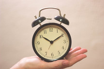 hand holding up an alarm clock 