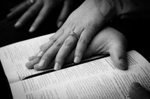 couples hands on a Bible 