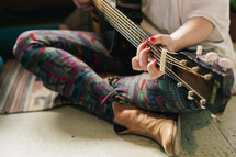 a woman sitting on the floor playing a guitar 