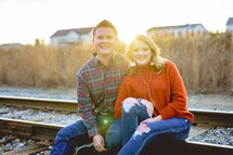 portrait of a couple sitting on train tracks 