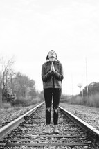 woman praying in the middle of train tracks 