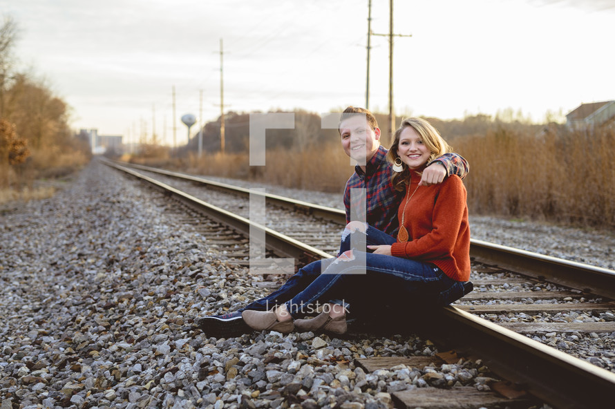couple sitting on train tracks 