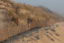 fence along sand dunes on a beach 