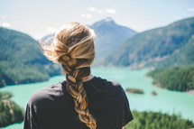 a woman with a braided ponytail with her back to the camera near Diablo Lake 