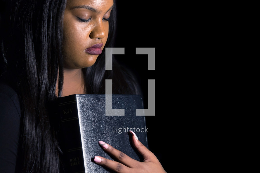 African American woman holding a Bible close to her heart 