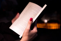 Close Up Woman’s Hand Holding a Book by a Fireplace