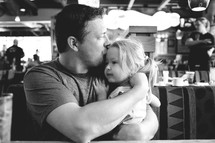 A father holding and kissing his little girl.