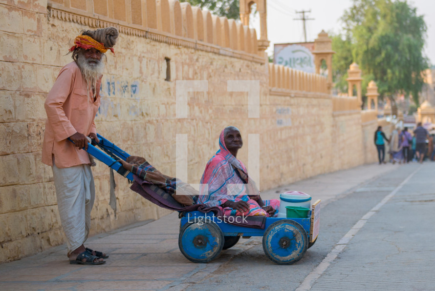 a man pushing his wife in a wagon India 