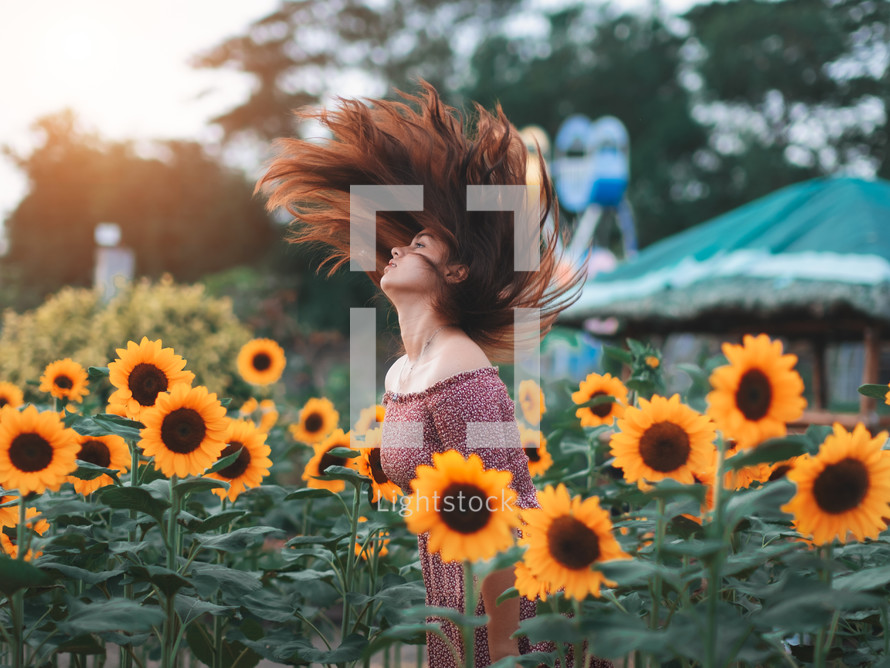 a teen girl flipping her hair in a field of sunflowers 