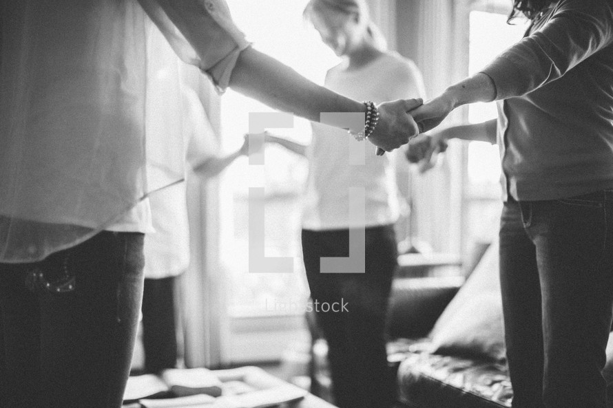 Women holding hands in a prayer circle during a bible study.