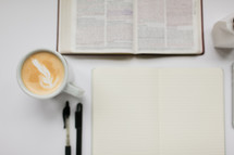 open Bible, pens, pages in a journal, and latte on a white background 
