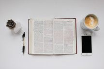 open Bible and other items on a desk 