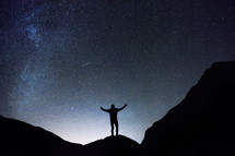 silhouette of a man standing under a starry sky 