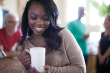 A smiling woman holding a coffee cup.