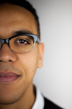 The face of a young man in glasses against a white background.