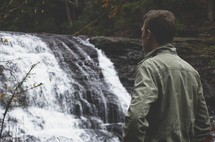 a man looking at a waterfall 