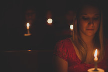 parishioners sitting in church pews holding candles at a Christmas Eve candlelight service 