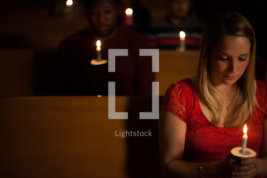 parishioners sitting holding candles at a Christmas Eve worship service 