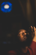 a man with head turned to God and praying hands in church 