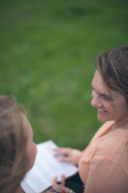 Smiling mother and daughter reading the Bible together.