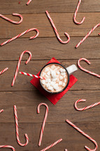 candy canes spread out on a table and a mug of hot cocoa
