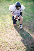 football player kneeling in prayer on the field 