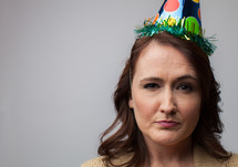 woman in a party hat with a frown 