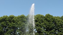 Fountain vertical jet of water, in front of trees and the sky