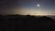 Parallax above mountains as eclipse totality moment of moon on sun flares	