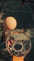 Young men playing basketball on an outdoor court on a sunny day