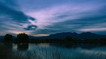 Time lapse of colorful clouds over mountains and a peaceful lake