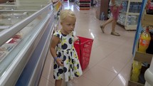 Little shopper with cart in the supermarket