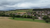 Aerial footage flying over field with distant German village