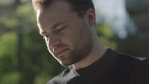 Young man reading his Bible outside on a warm sunny day