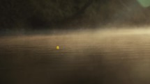 Young fly fisherman casting on a foggy river at sunrise