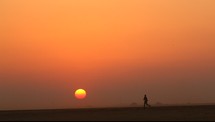 a man running in a desert at sunset 