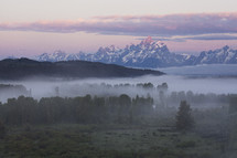 snow mountain peaks and fog over forest 
