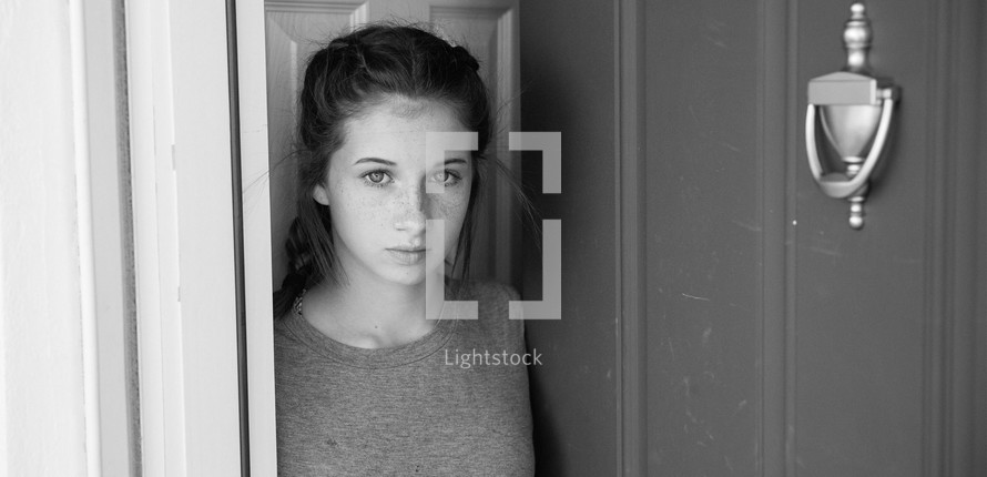 teen girl standing at a front door 