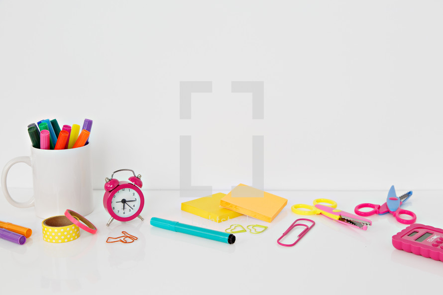 calculator, scissors, markers, and paperclips on a white background 