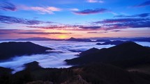 Misty mountains at sunrise: moving clouds and swirling fog create a tranquil and enchanting scene