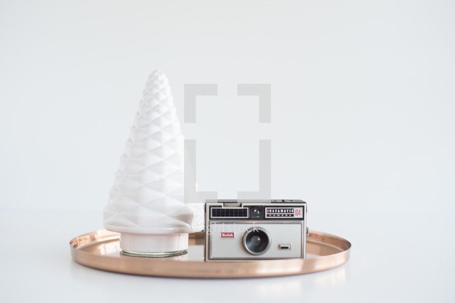 tray, tree figurine, and camera on white background 