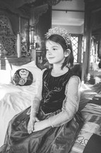 a little girl on a bed dressed up like a princess 