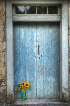 vase of sunflowers in front of a blue door 