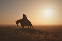 a man riding a horse at sunset 